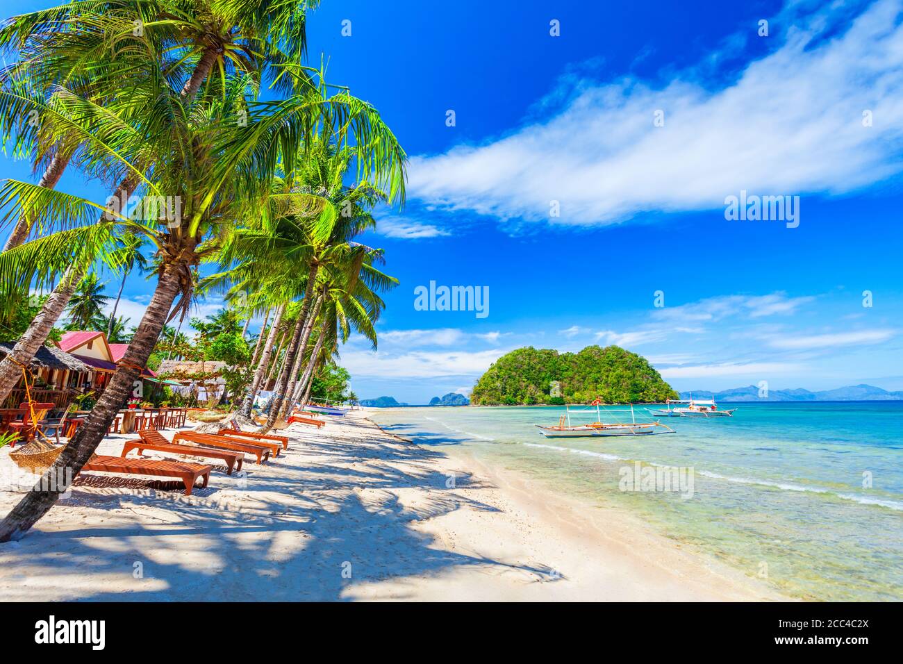 Beach with white sand, coconut palms and turquoise water in El Nido province, Palawan island in