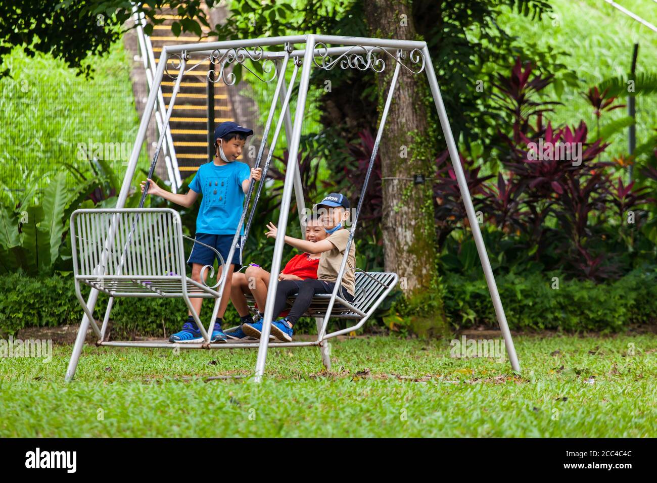 Three japanese asia boys playing on the swing having fun at outdoor location. Stock Photo