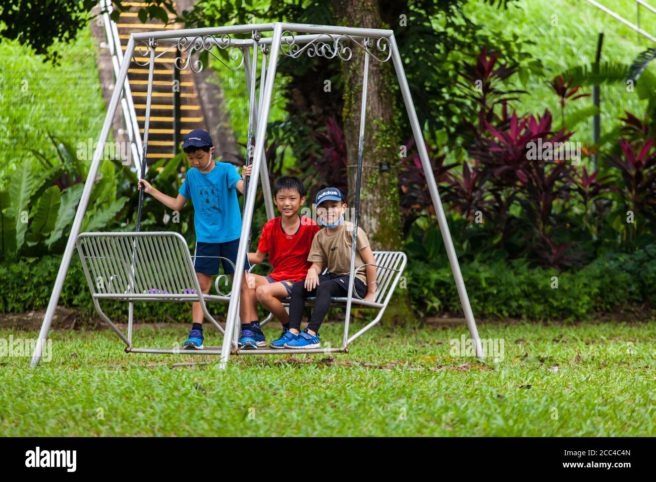 Asian boys standing and sitting on the swing. Stock Photo