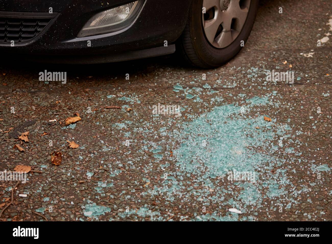 Broken glass on the road around a parked car Stock Photo