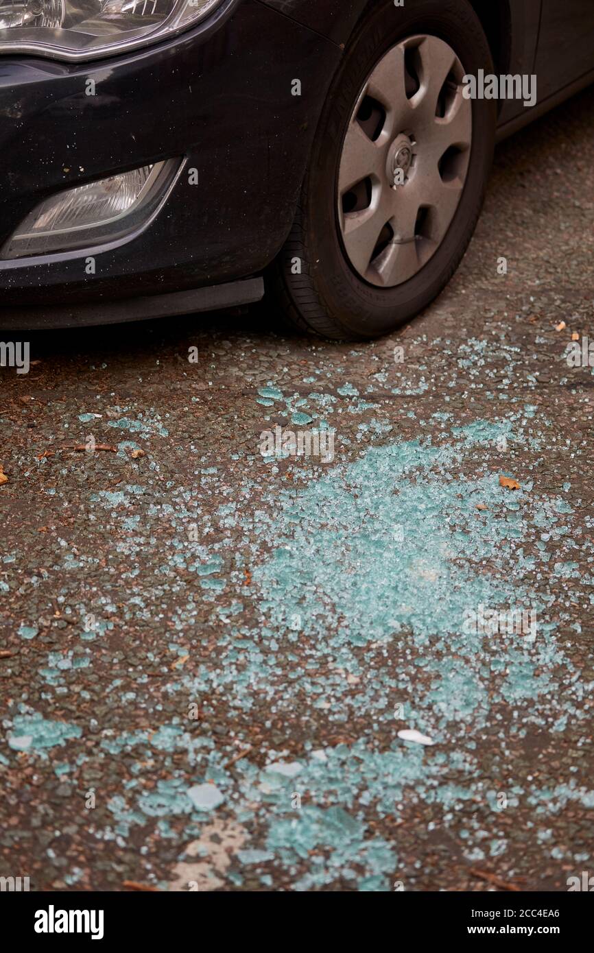 Broken glass on the road around a parked car Stock Photo