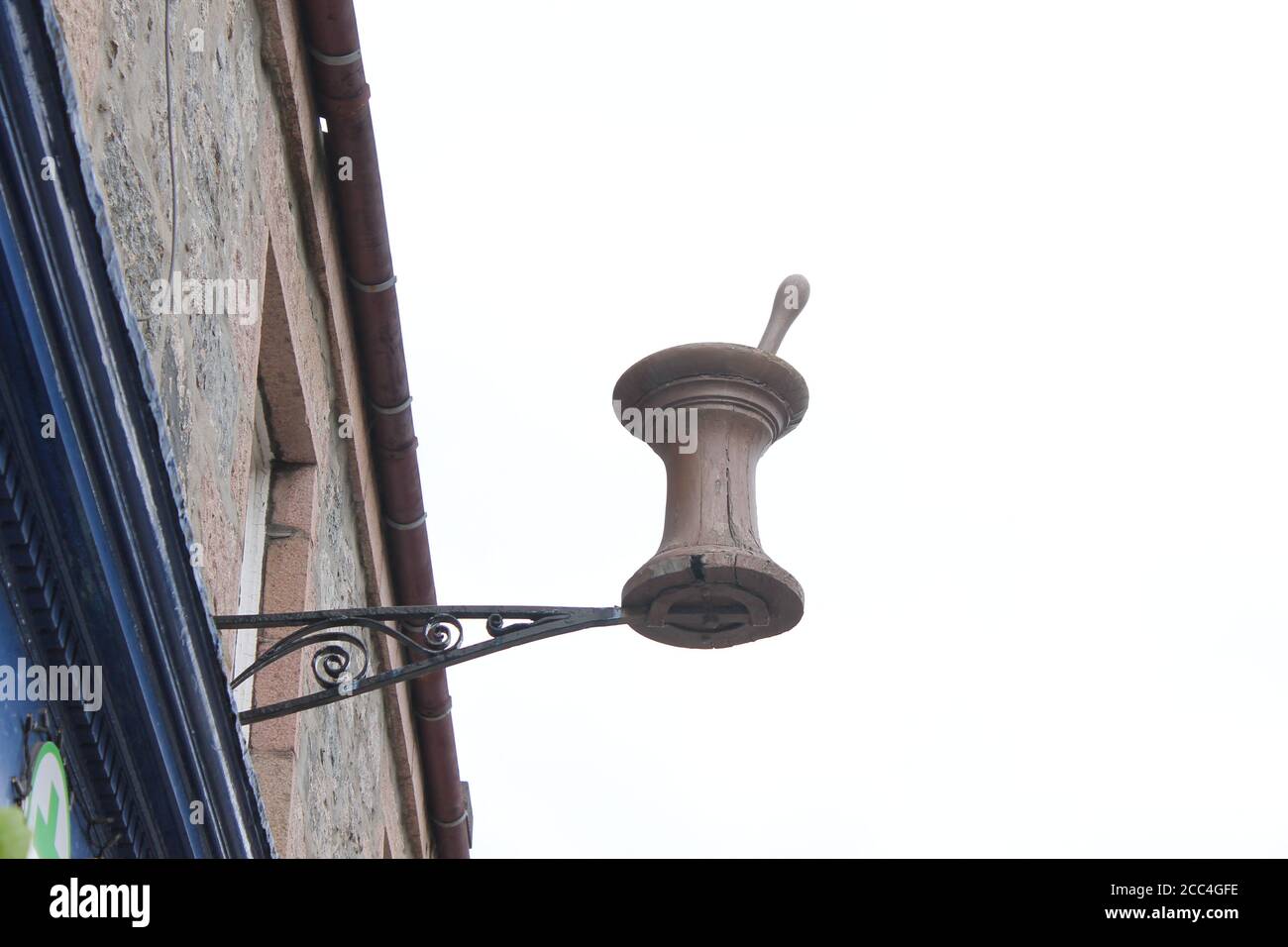 Hanging wooden mortar and pestle high up on pharmacy building, with copy space Stock Photo