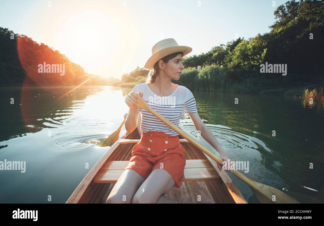 Young woman paddling canoe, couple enjoy boat ride on the summer sunset