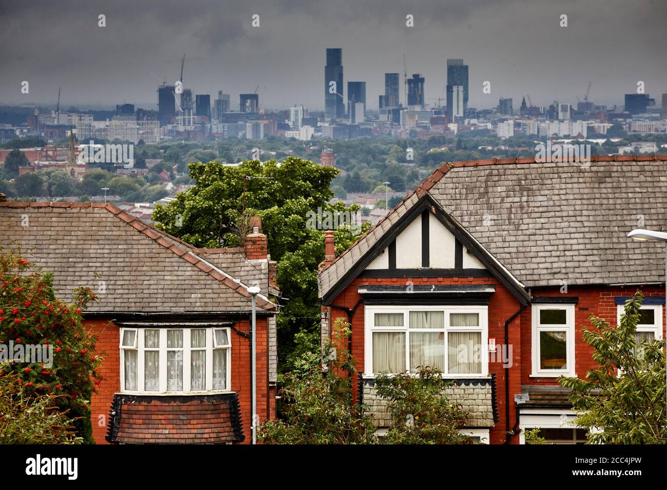 Housing stock in Oldham with the Manchester Skyline behind Stock Photo