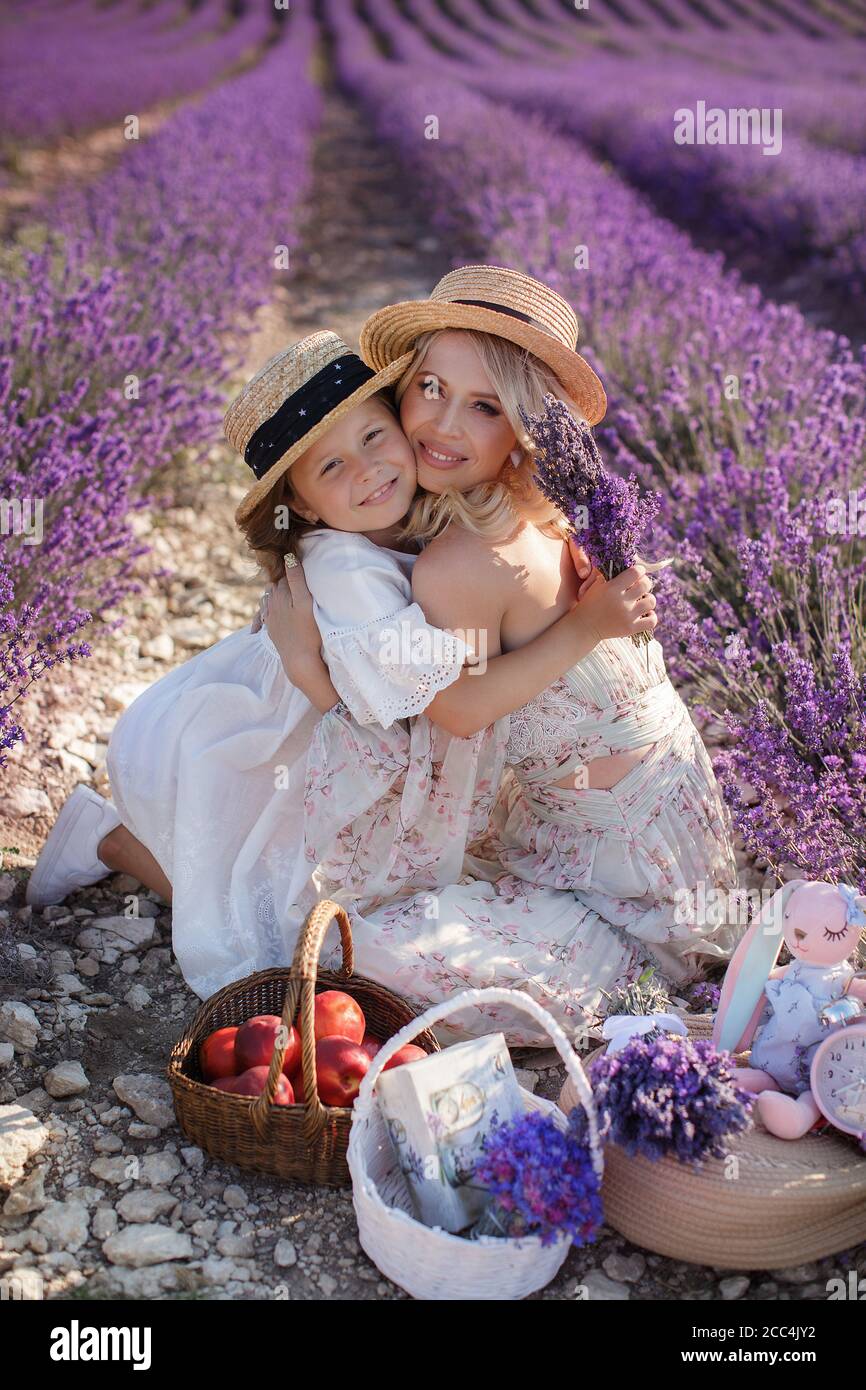 woman with daughter in white dresses having fun in lavender field in summer. family portraits Stock Photo
