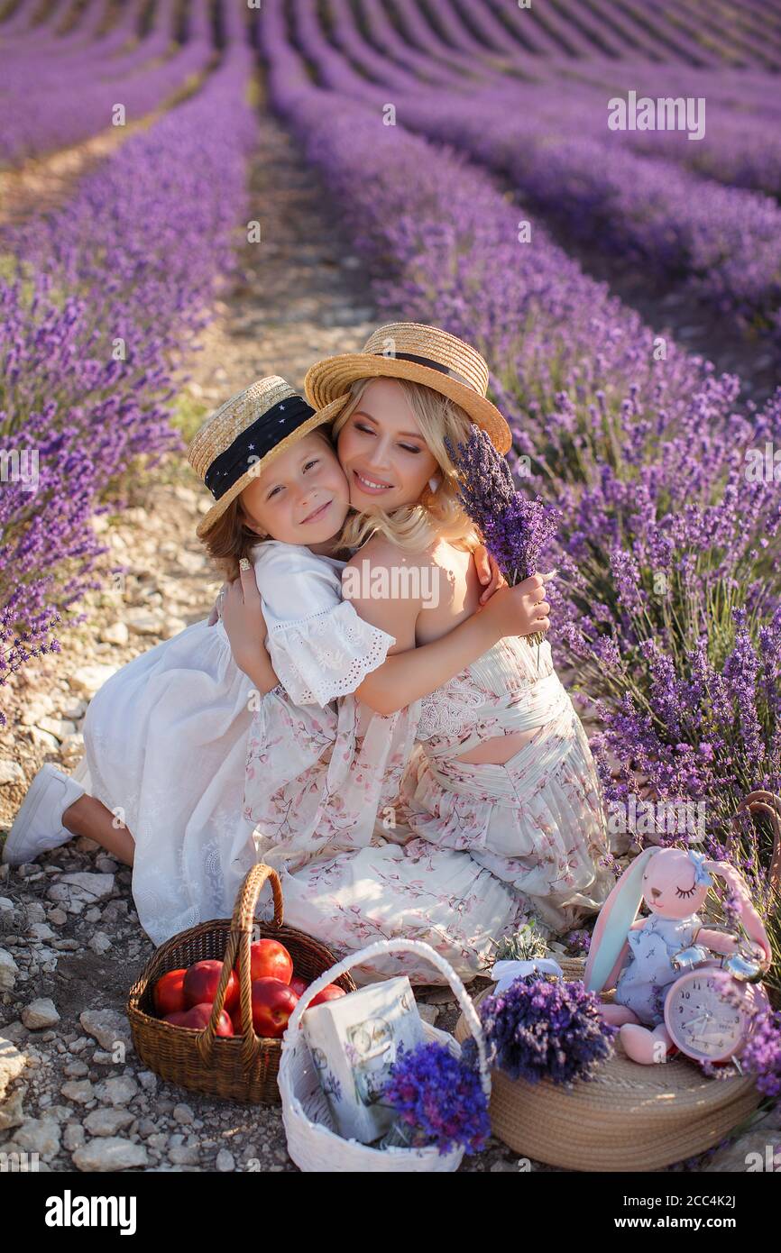 woman with daughter in white dresses having fun in lavender field in summer. family portraits Stock Photo