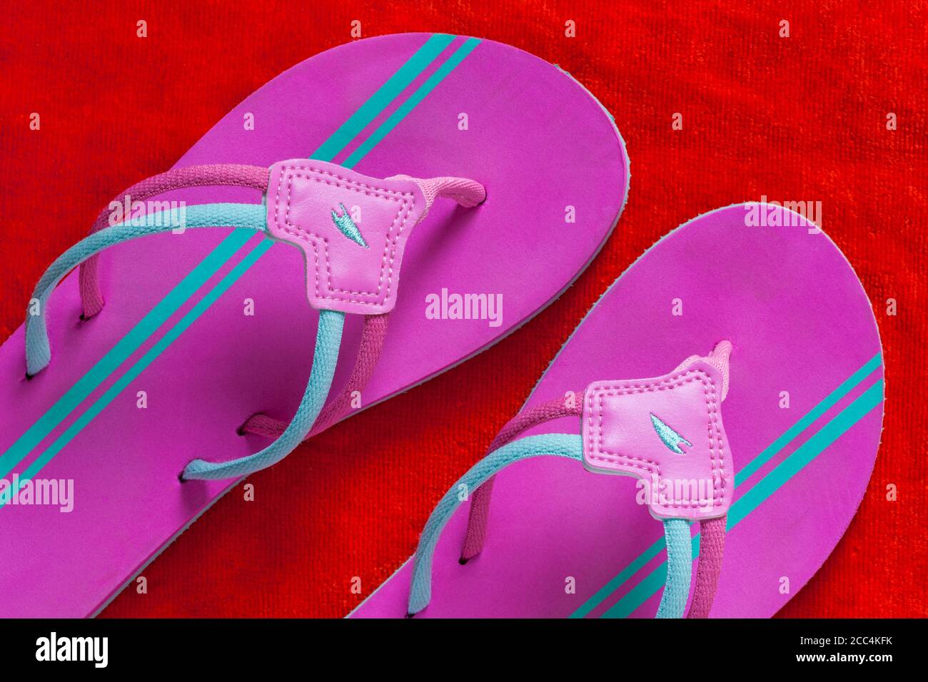 pink and turquoise flip flops on orange coloured towel Stock Photo