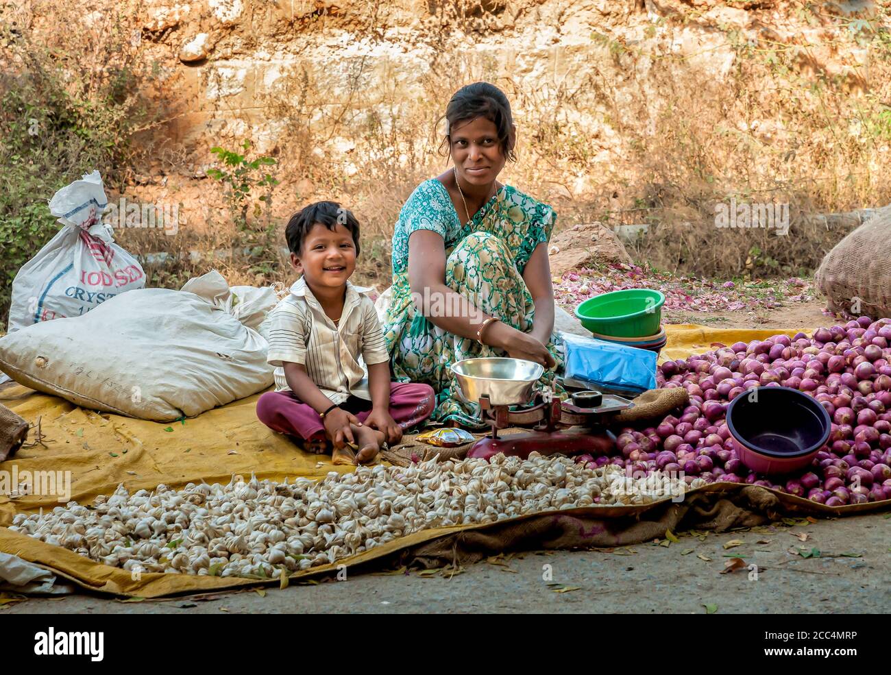Puttaparthi, Andhra Pradesh, India - January 13, 2013: Mother and son selling garlic and onions at street market of Puttaparthi, India Stock Photo
