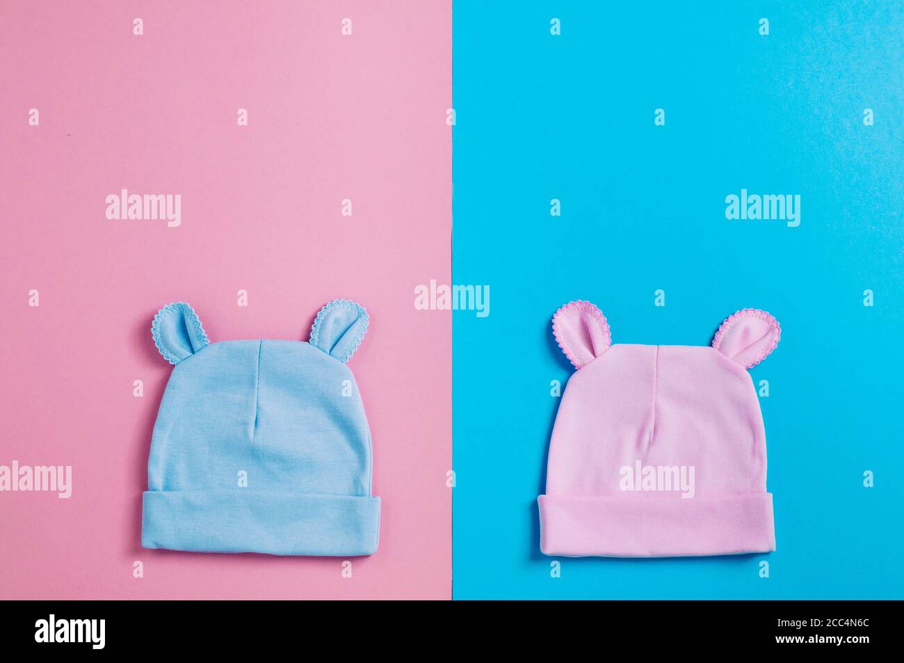 Babys caps with ears over pink and blue background with copy space Stock Photo