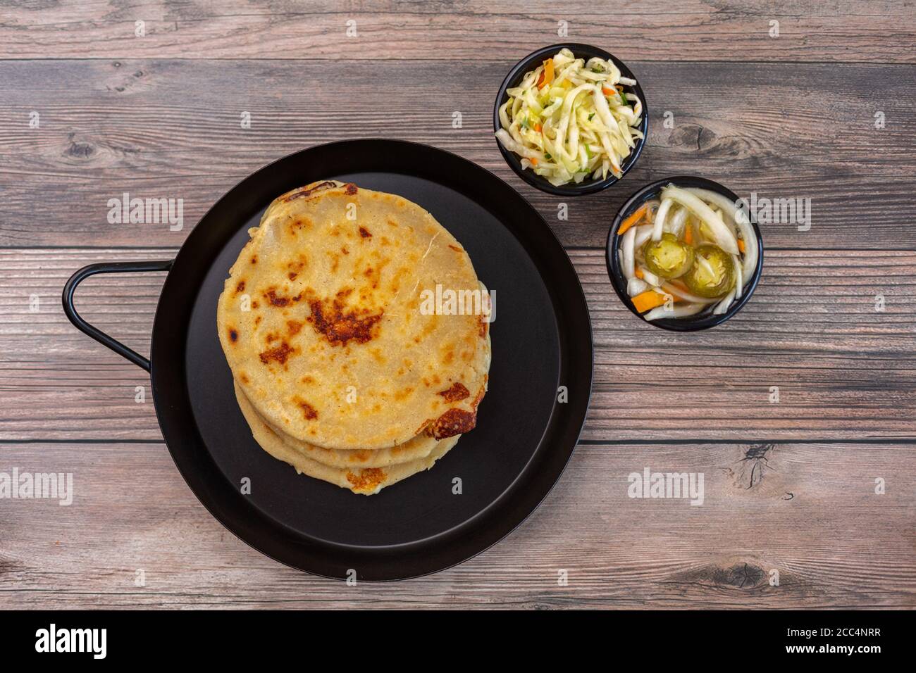 Top  view  of the delicious pupusas  on the pan next to salads in bowls Stock Photo