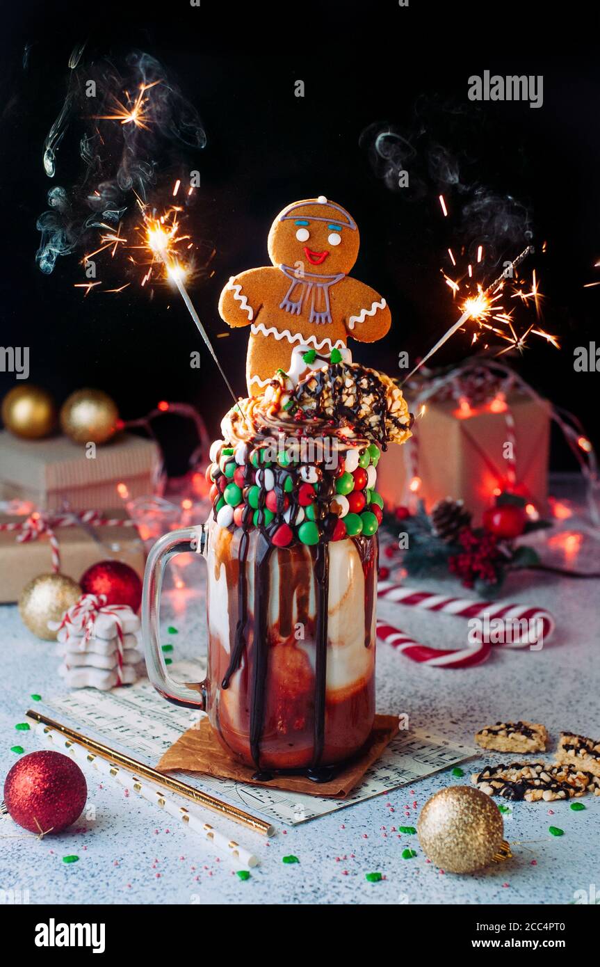 Christmas freak shake with sparkler bengal lights topping with gingerbread man on party table Stock Photo
