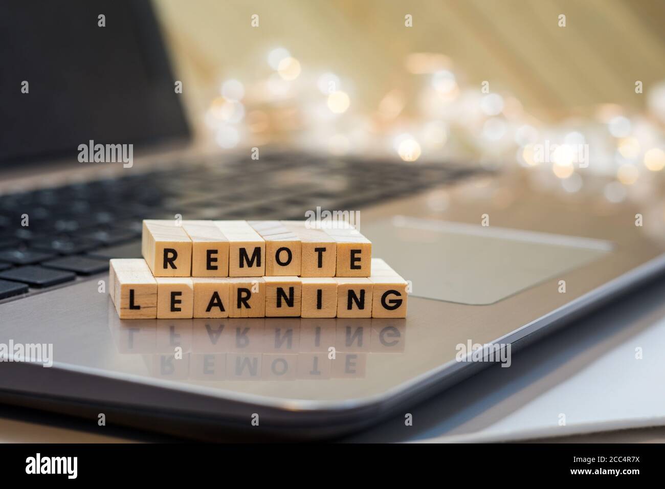 REMOTE LEARNING virtual learning concept with wood block letters on laptop.  Distance learning, remote learning, virtual learning. Stock Photo