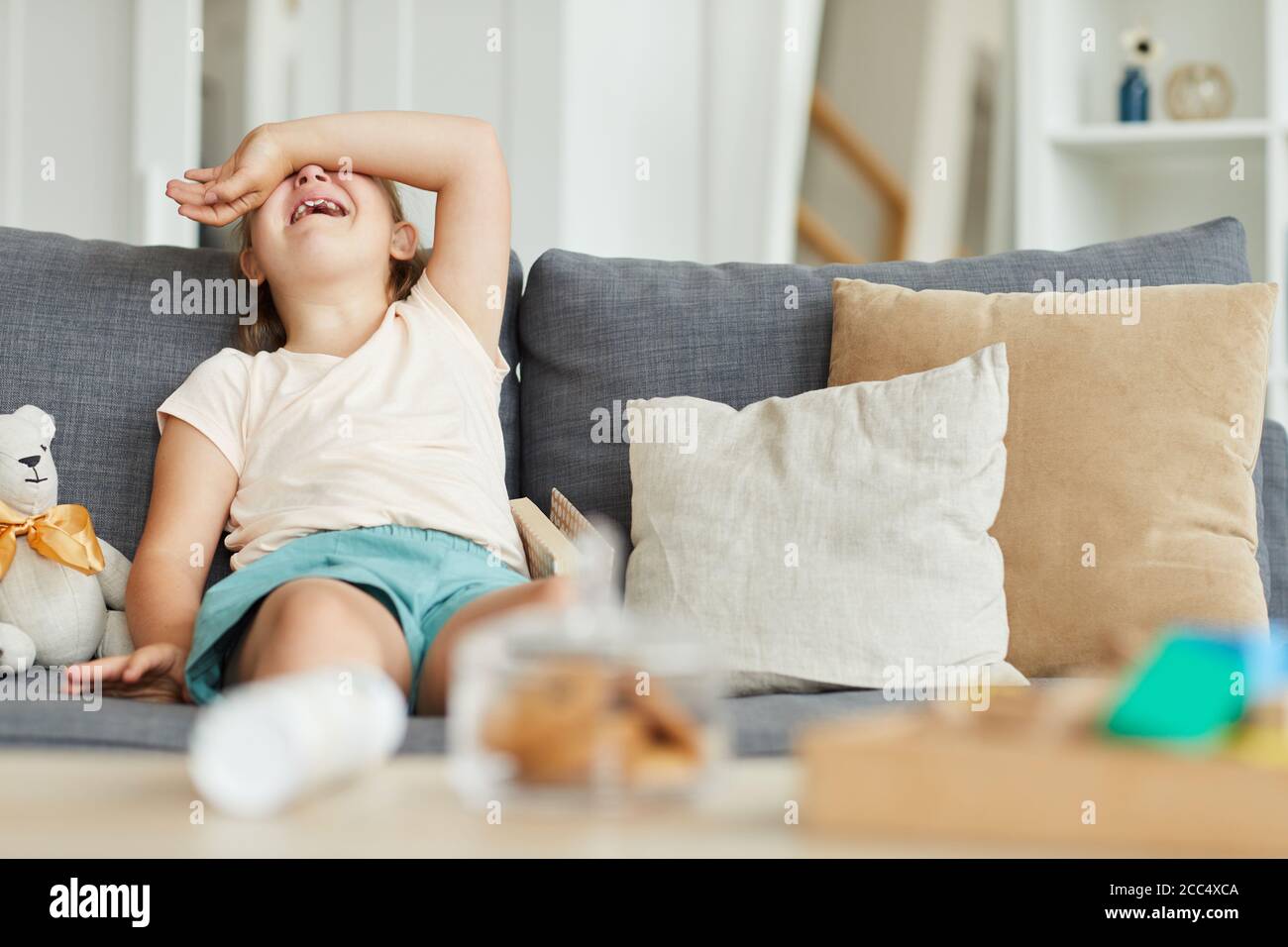 Little girl sitting on sofa and laughing she is in the living room at ...