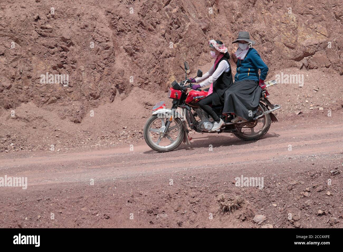 Two women on Chinese motorcycle, mountain road in south Qinghai Province, China 27th August 2017 Stock Photo