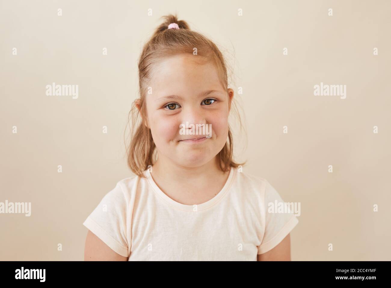 Portrait of cute little girl looking at camera against the white ...
