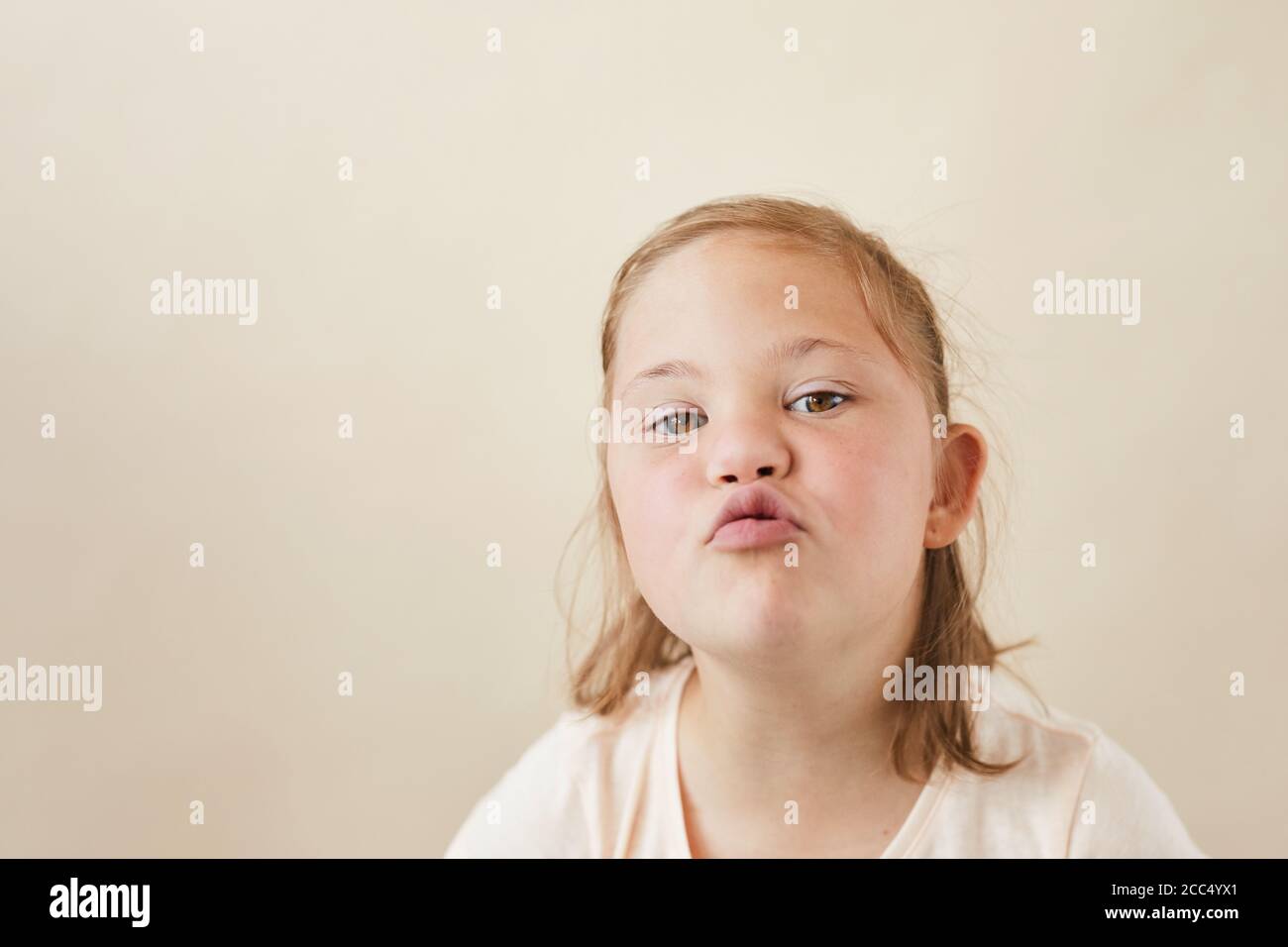 Portrait of little girl with down syndrome sending the kiss to camera isolated on white background Stock Photo