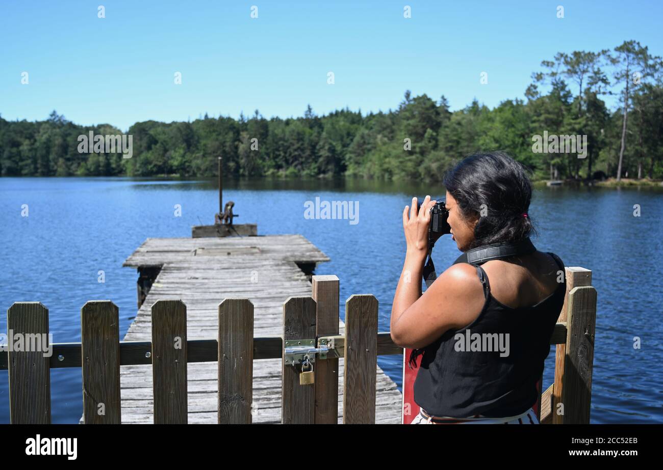 Asian-African Mestizo woman seen from the side takes a picture of a lake. Stock Photo