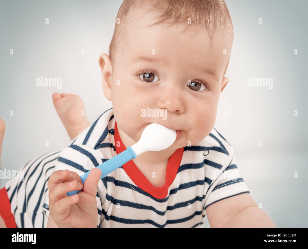 Nine month old baby lying in the bed with spoon Stock Photo Alamy