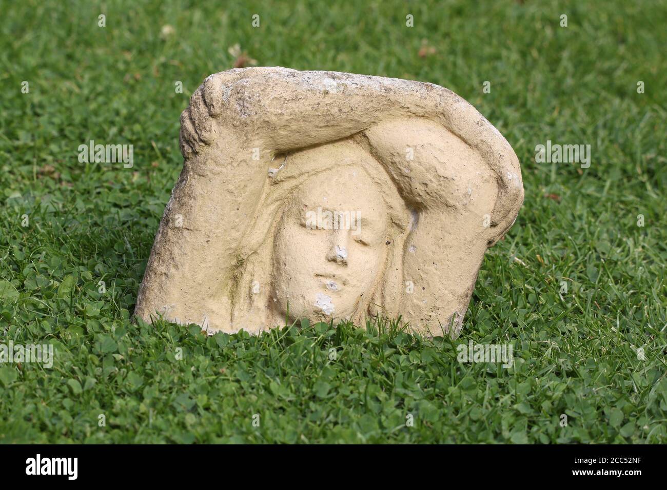 statue of girl sinking into lawn Stock Photo