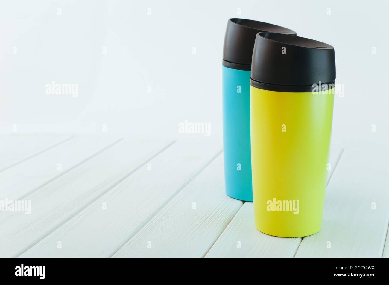 Color thermos mugs on the white wooden table Stock Photo