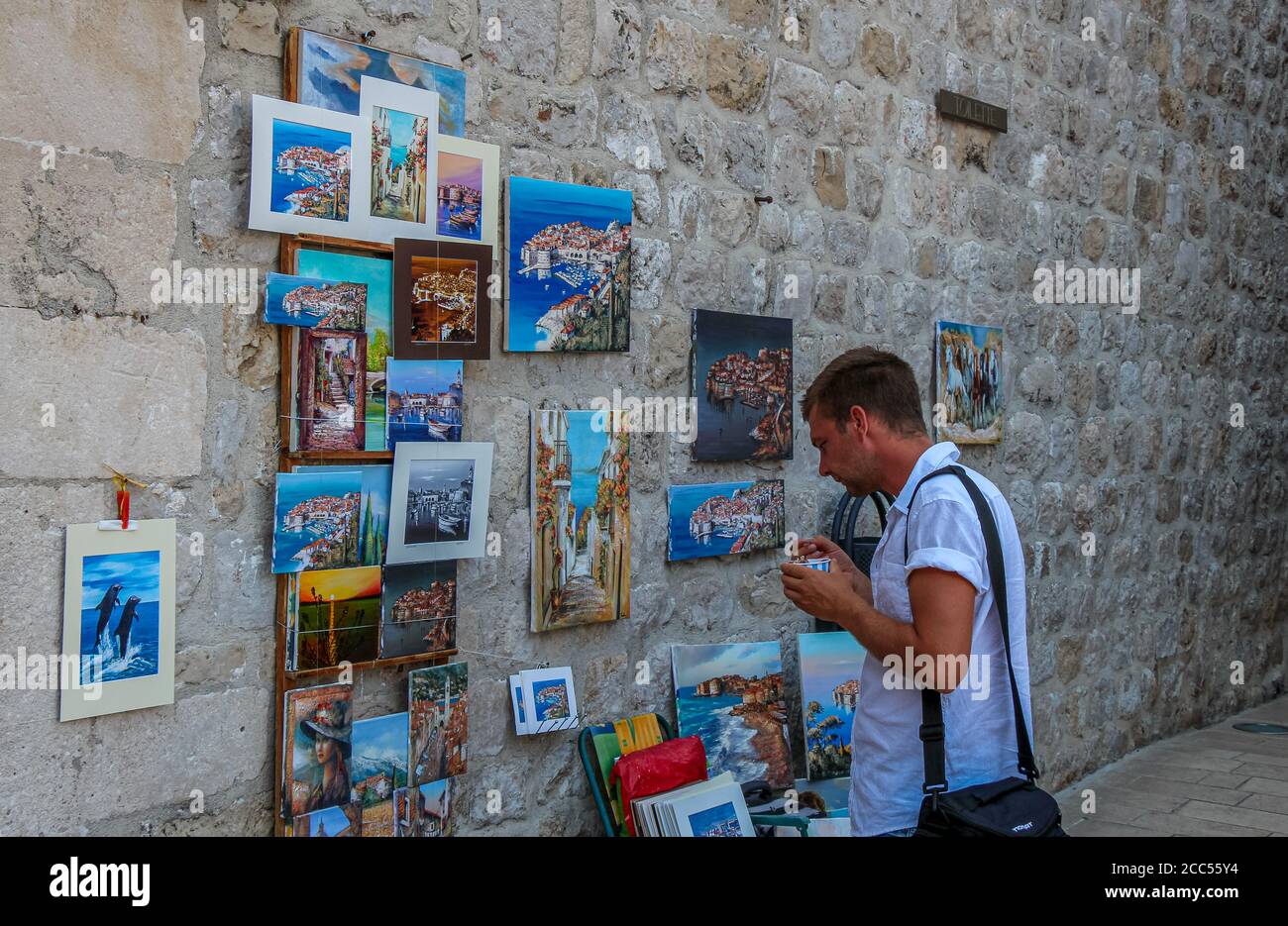 Dubrovnik, Croatia - July 15th 2018: A tourist eating ice cream, admiring artwork in Dubrovnik's historic old town in summer, Croatia Stock Photo