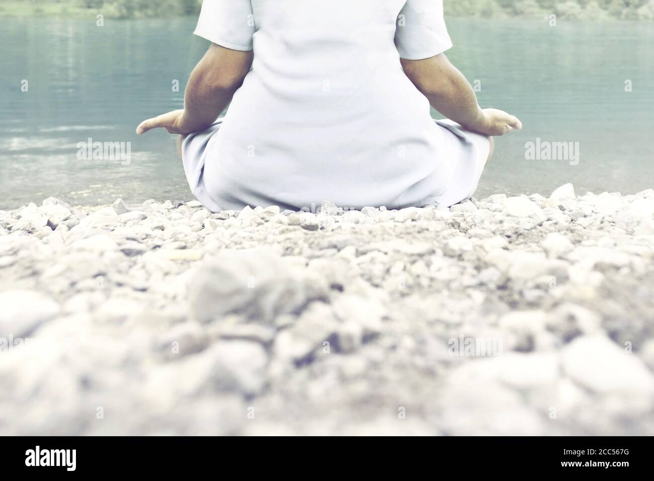woman doing yoga exercises in front of a spectacular mountain lake ...