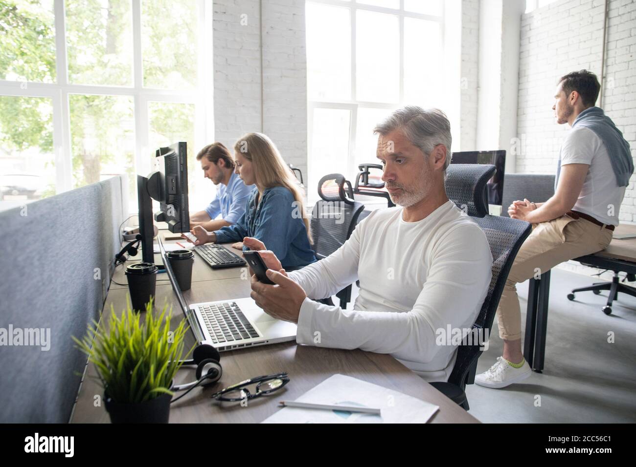 Man Working At Desk In Busy Creative Office. Stock Photo