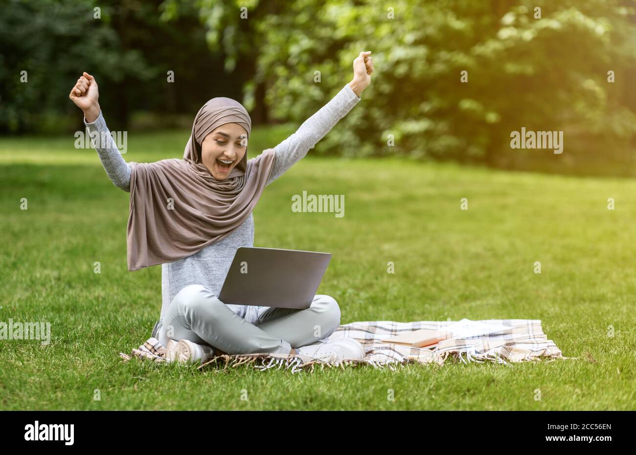 Emotional muslim girl looking at laptop and screaming Stock Photo