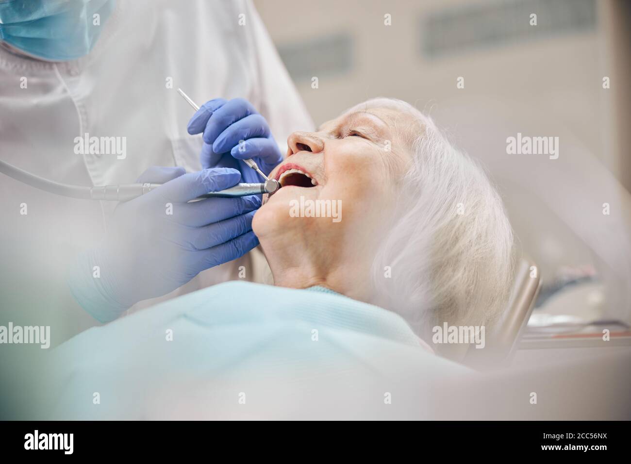 Dentist treating woman patient using drill on her teeth Stock Photo Alamy