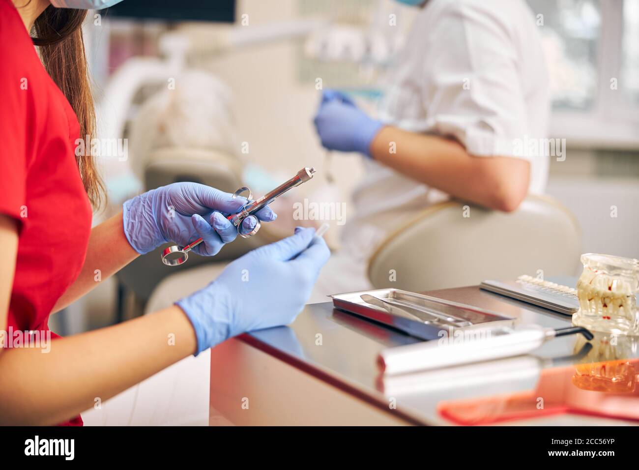 Dentist hands in rubber protective gloves holding equipment for work Stock Photo