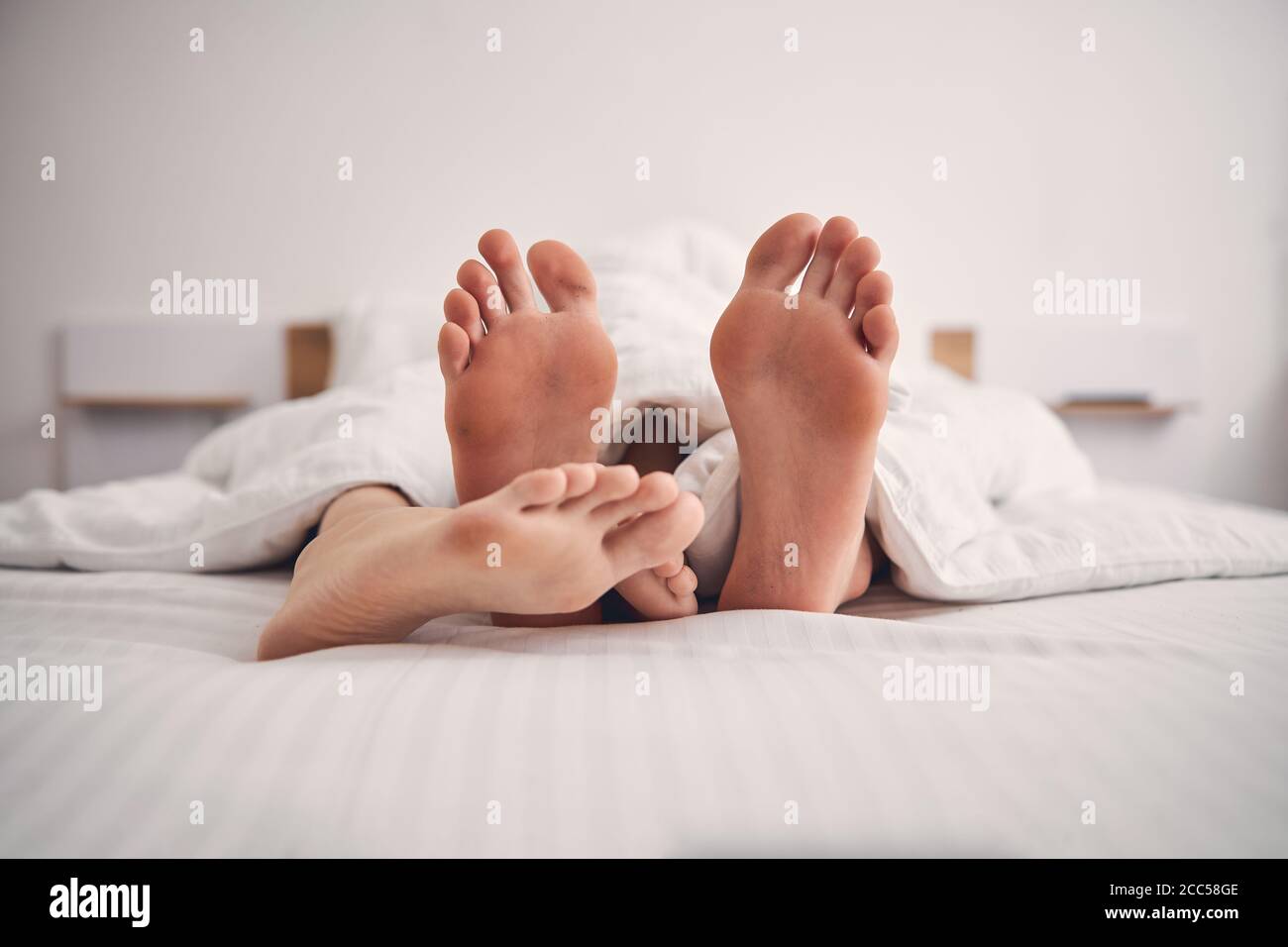 Close up of two people feet in bed Stock Photo - Alamy