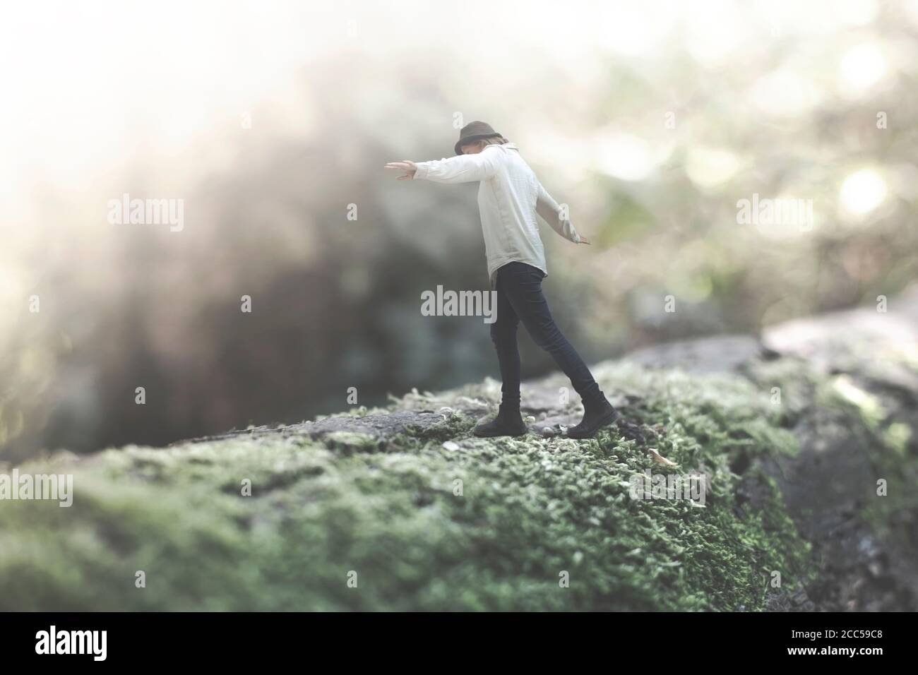 surreal moment of a woman walking balanced on a giant tree trunk in the forest Stock Photo