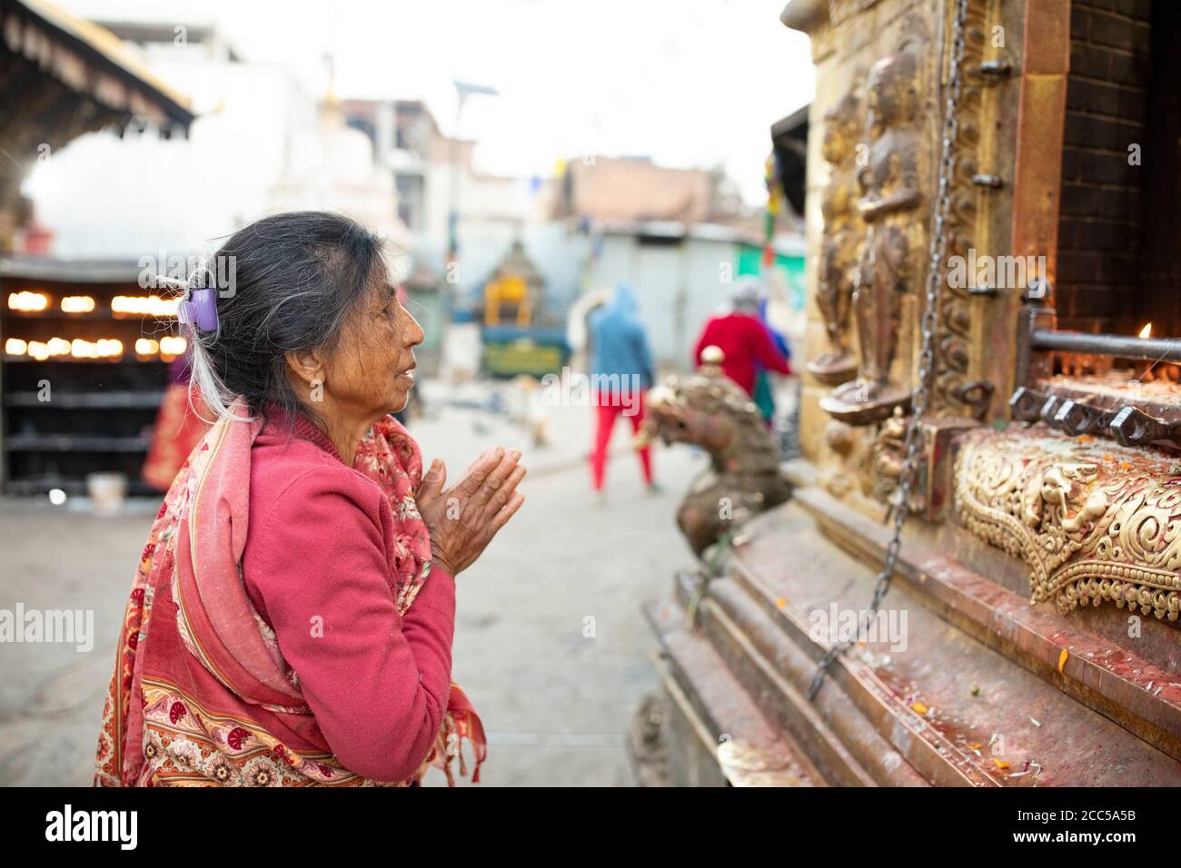 Woman praying with folded hands at a shrine at Swayambhunath stupa in Kathmandu, Nepal. Stock Photo