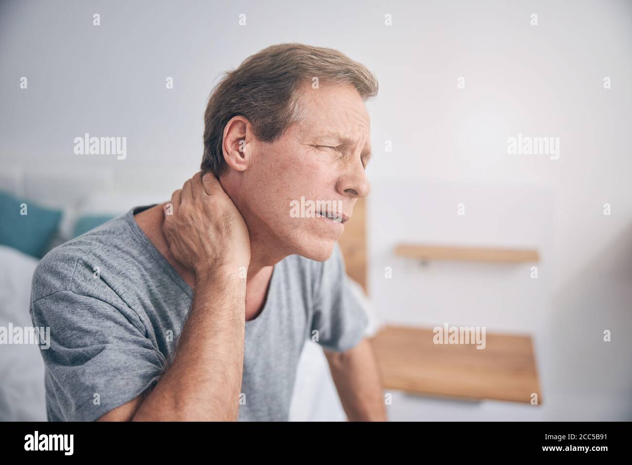 Upset mature man suffering pain in neck Stock Photo