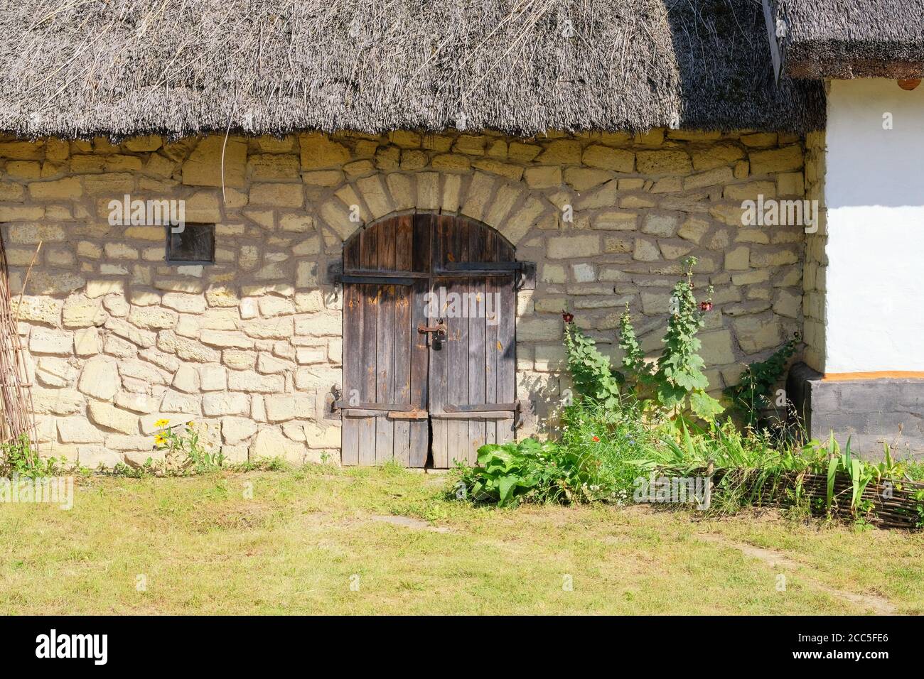 Old rural house with thatched roof. Village is preserving rustic traditions and culture. Stock Photo