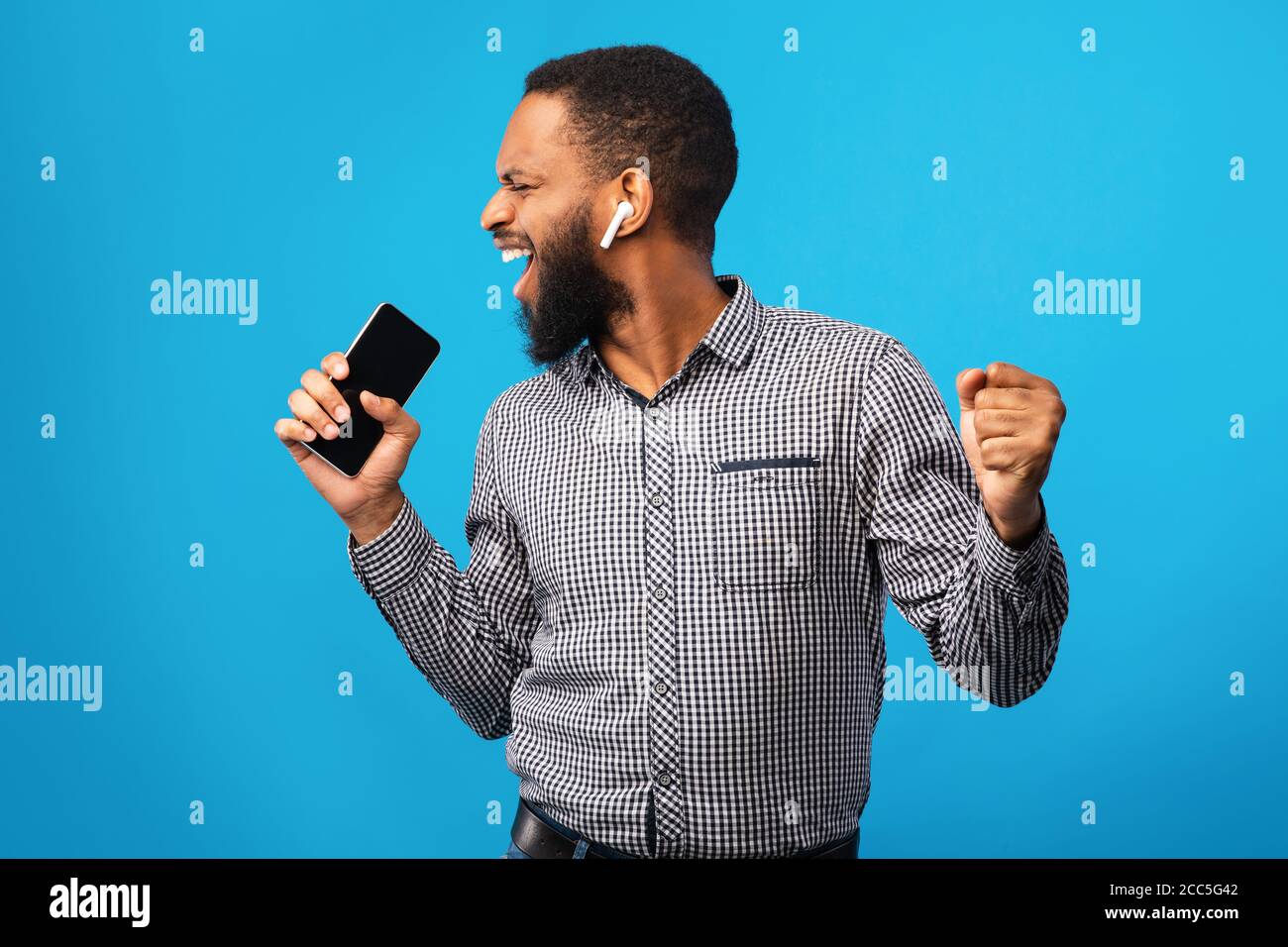 Happy afro man singing using smartphone as mic Stock Photo