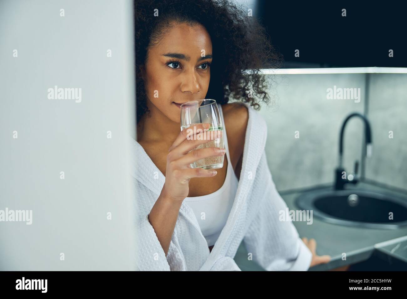 Thoughtful dark-haired woman leaning on the countertop Stock Photo