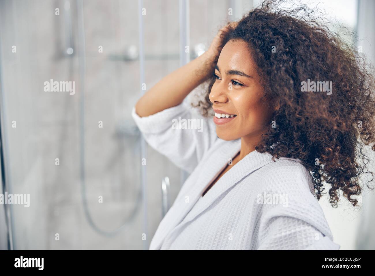 Smiling female standing before the bathroom mirror Stock Photo