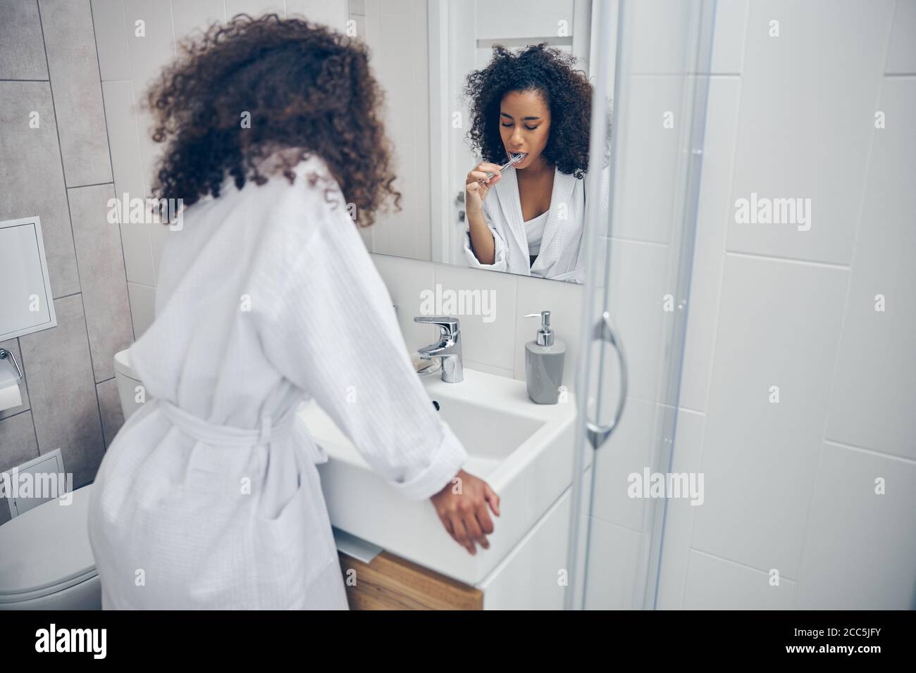 Woman brushing her teeth with her eyes closed Stock Photo