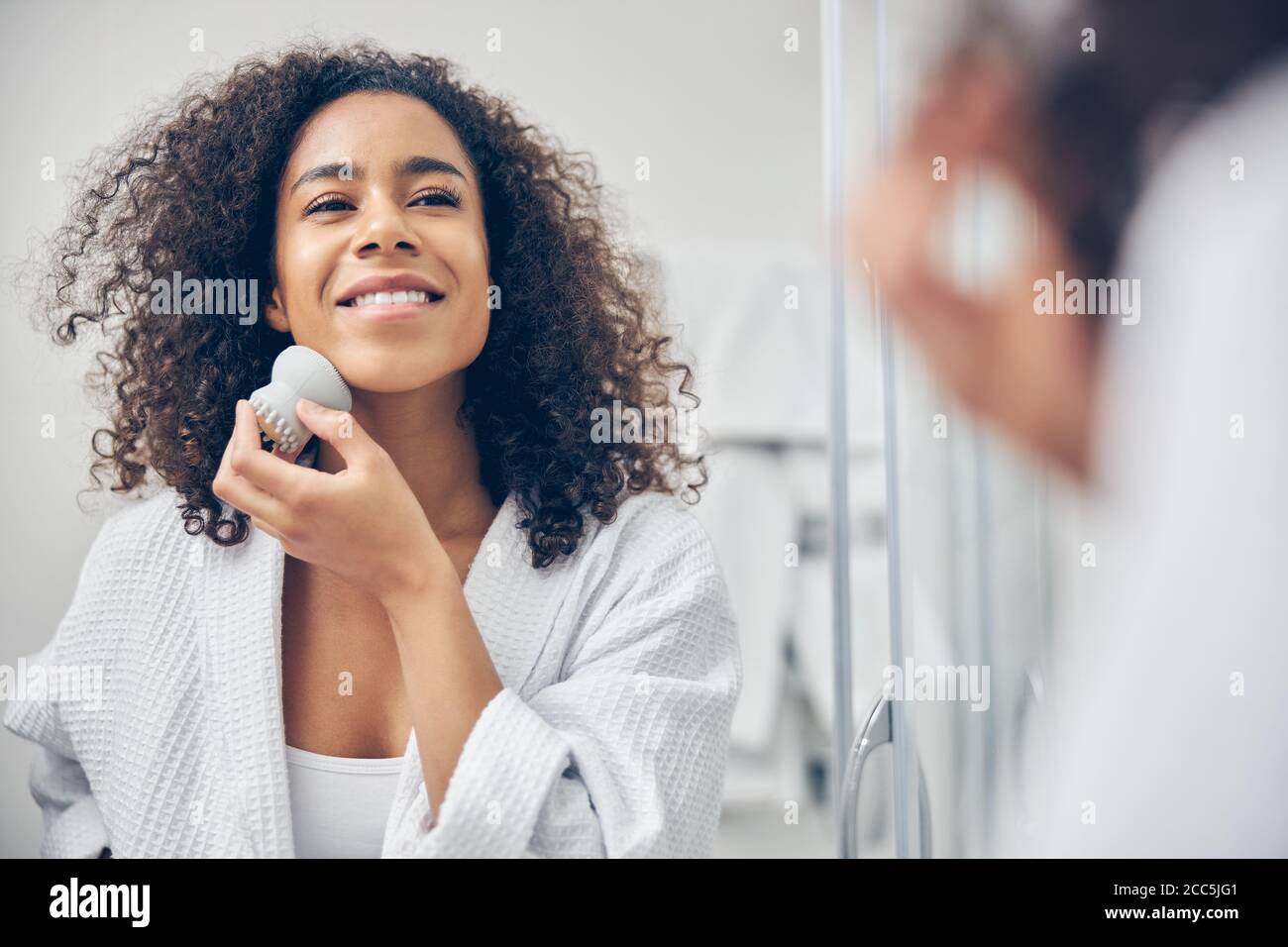 Pleased young woman performing an exfoliation procedure Stock Photo