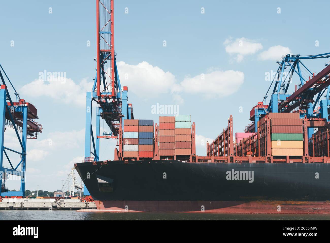 front section of large container ship at pier unter gantry cranes against blue sky Stock Photo