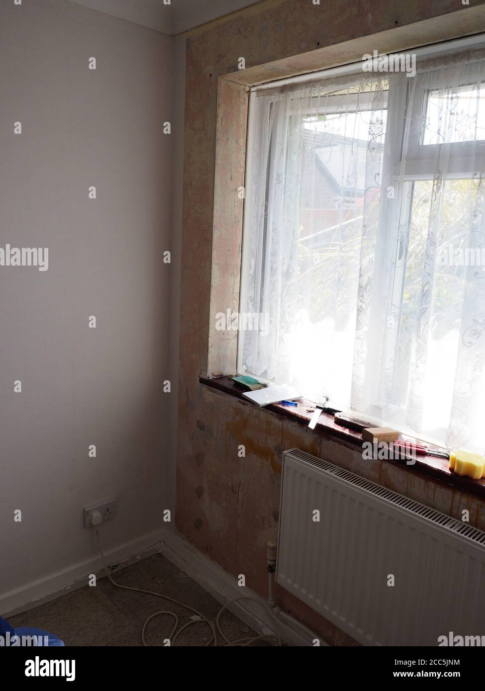 a room being decorated showing partly papered walls and a tools on windowledge Stock Photo