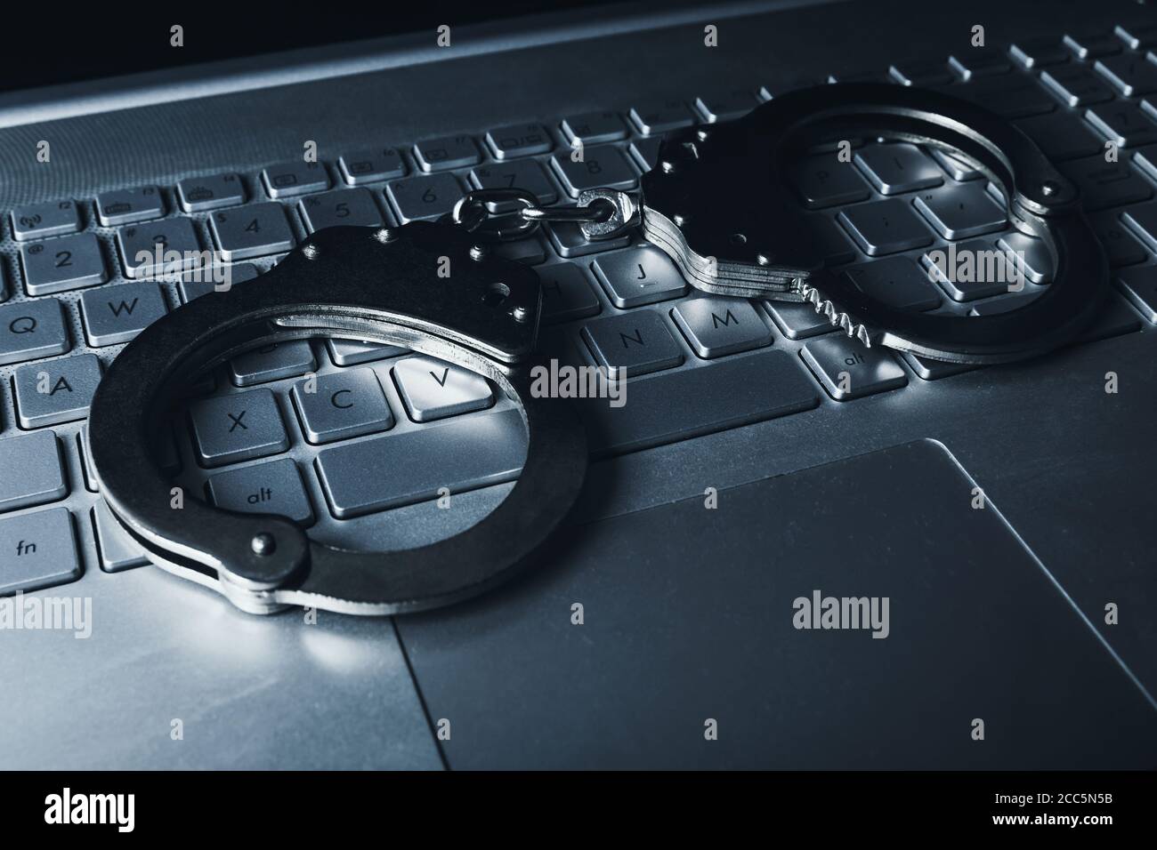 internet fraud cyber crime concept - handcuffs on laptop keybpord Stock Photo