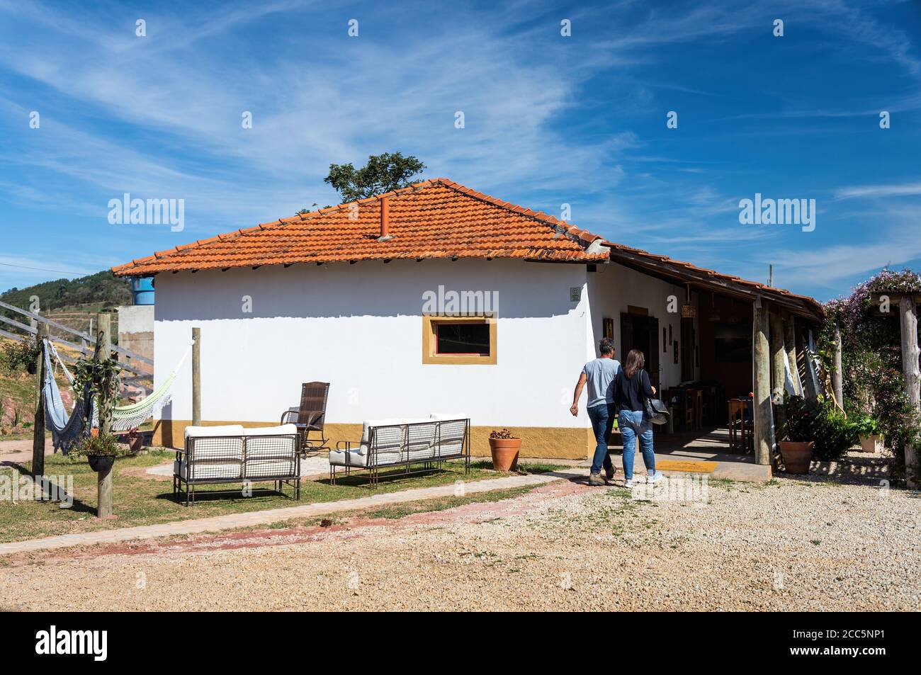Facade of cosy Casa da Serra restaurant under sunny blue sky while a couple walks in for lunch. Restaurant located at KM 60 of Salvador Pacetti road. Stock Photo