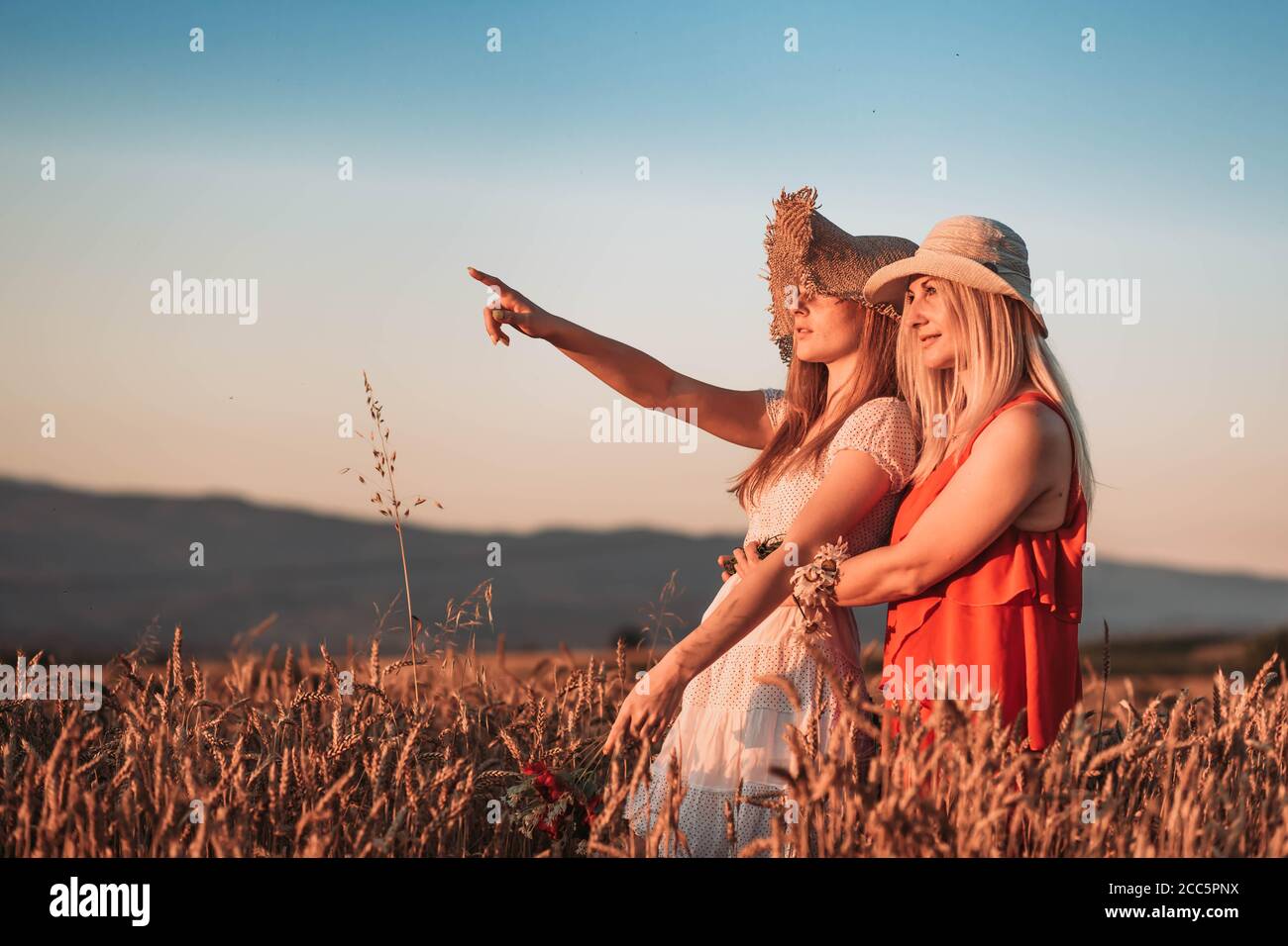 Mother and daughter hugging and looking at something. Girl pointing at something Stock Photo