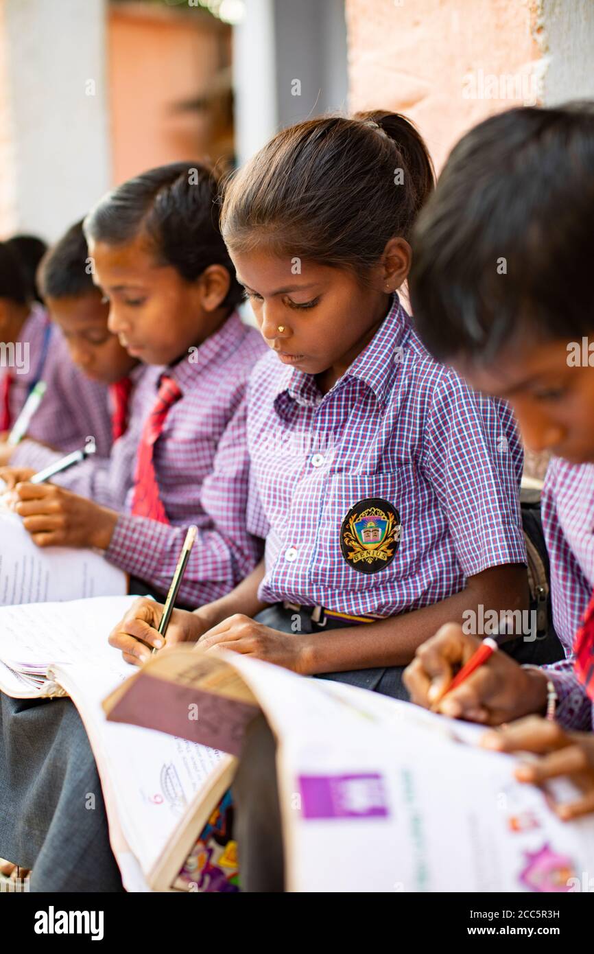 Primary school students in uniform attend school together and study with textbooks and writing instruments in Bihar, India. Stock Photo