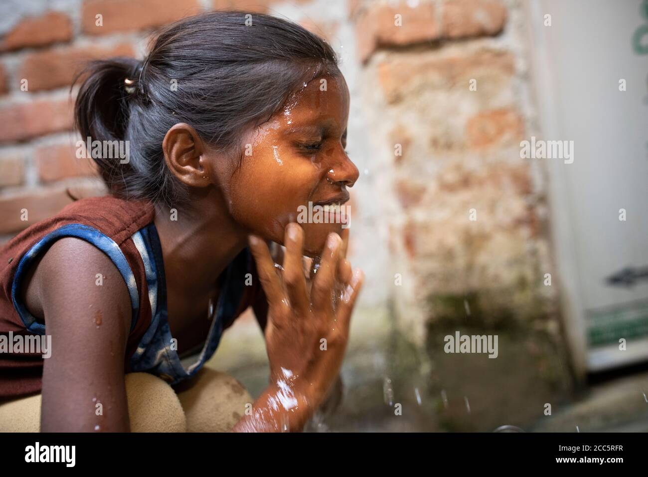 Anu Kumari (10), washes her face with water drawn from the new tap which her mother had installed recently in the family’s house in Bihar, India. Most people in rural India cannot running water in their own home, but Anand’s family’s participation with Partnership Bihar has greatly increased their standard of living. Partnership Bihar is a Lutheran World Relief initiative that brings better farming techniques, high-quality seeds, improved nutrition for families, and microfinance self-help groups to communities in one of India’s poorest states.   Pradan (Professional Assistance for Development Stock Photo