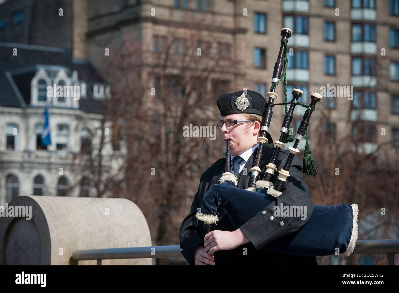 Bagpipe player dressed in traditional scottish tartan playing the