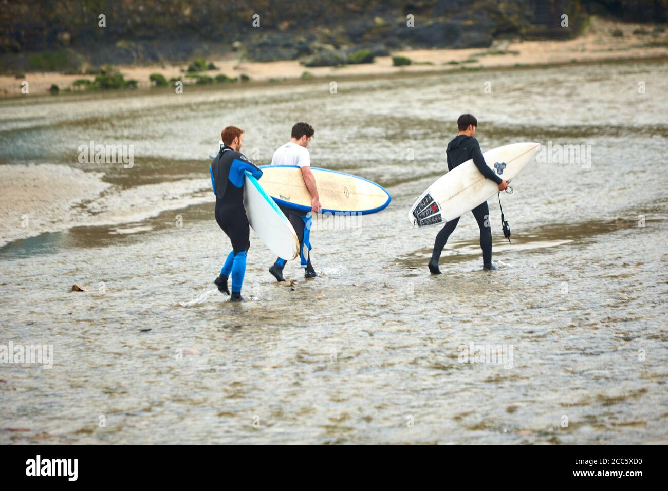 People walking with surf boards on Perranporth beach in Cornwall on Christmas Day Stock Photo