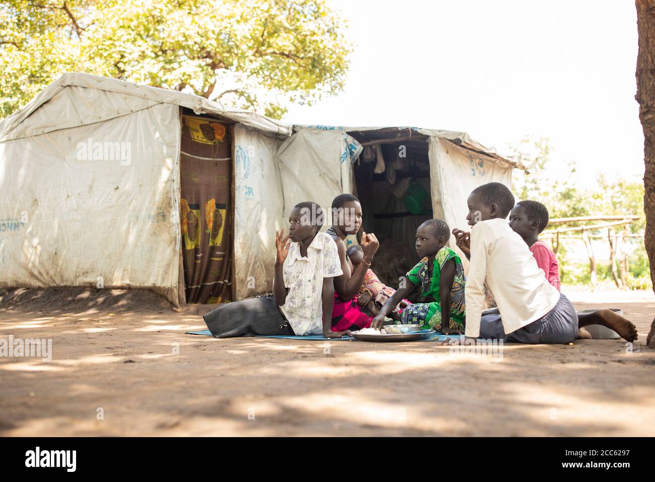 A family from South Sudan shares a meal together in Palabek Refugee Settlement in northern Uganda, East Africa. Stock Photo